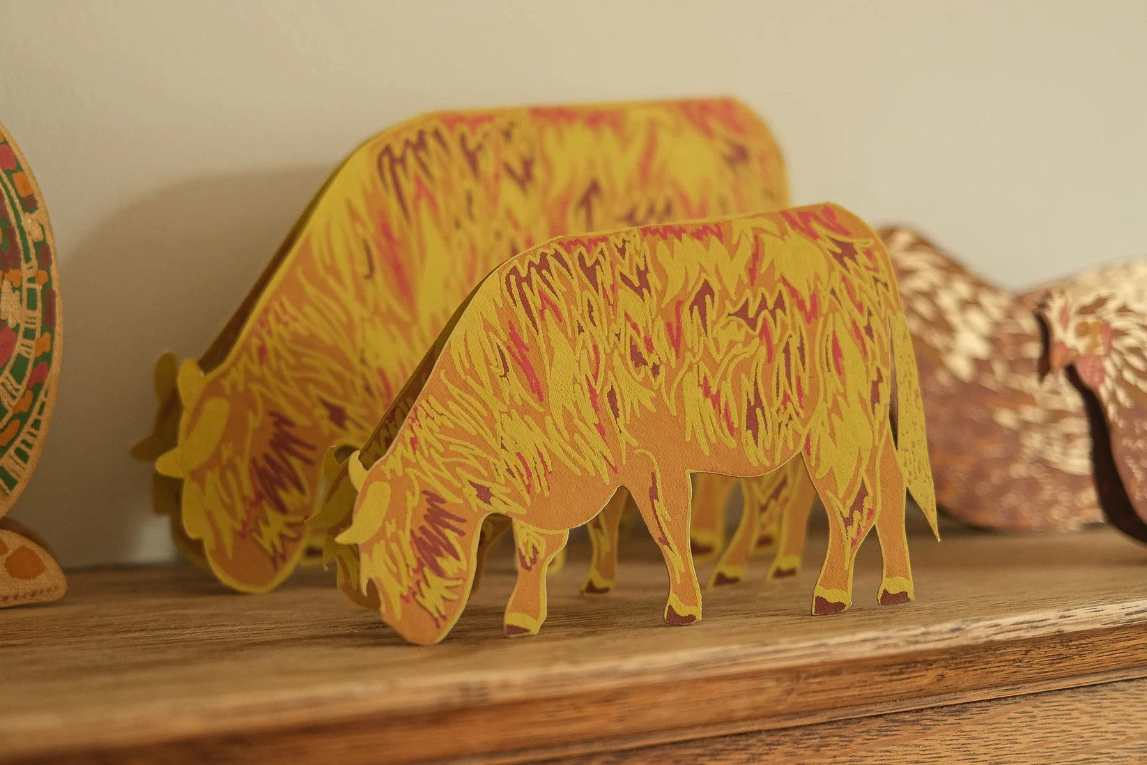 3D paper model of a highland cow on a shelf.