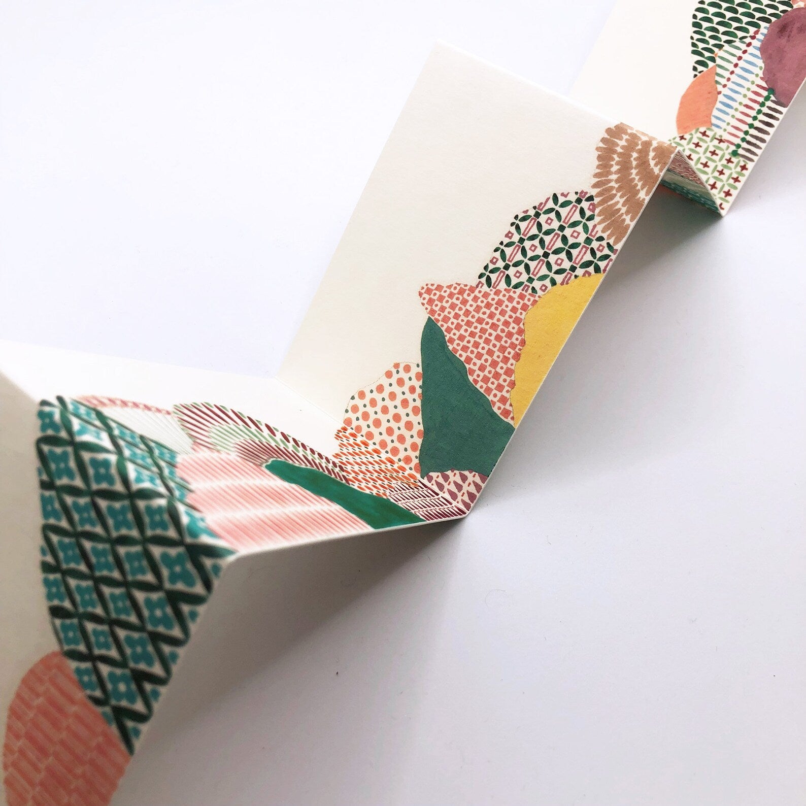 Colourful geometric patterned paper on a white background.