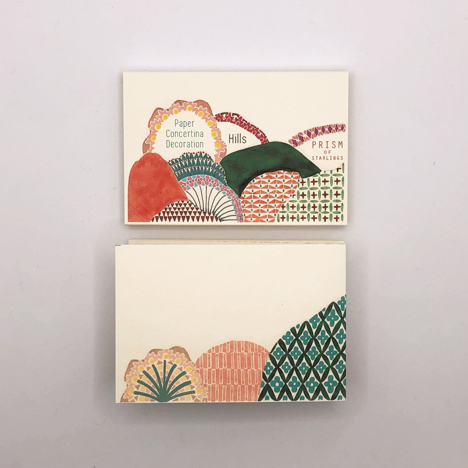 Two decorative paper concertina books with geometric patterns on a gray background.