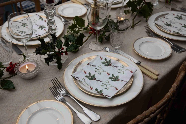 Elegant table setting with floral-patterned plates and napkins on a beige tablecloth.