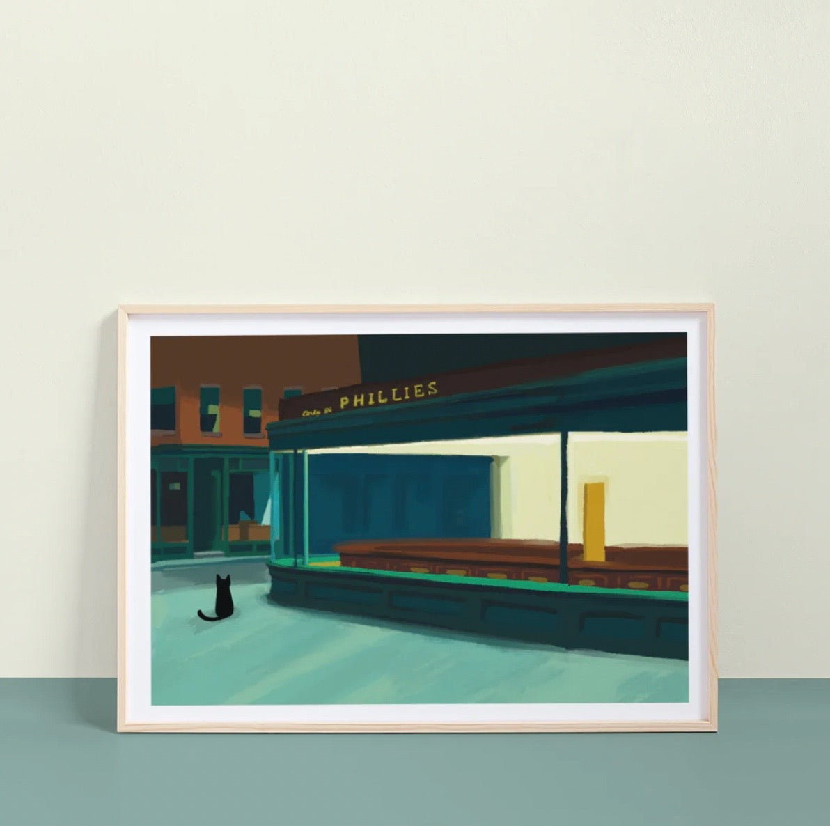Framed artwork of a city street scene with a cat sitting on the sidewalk, featuring a 'Phillies' sign.