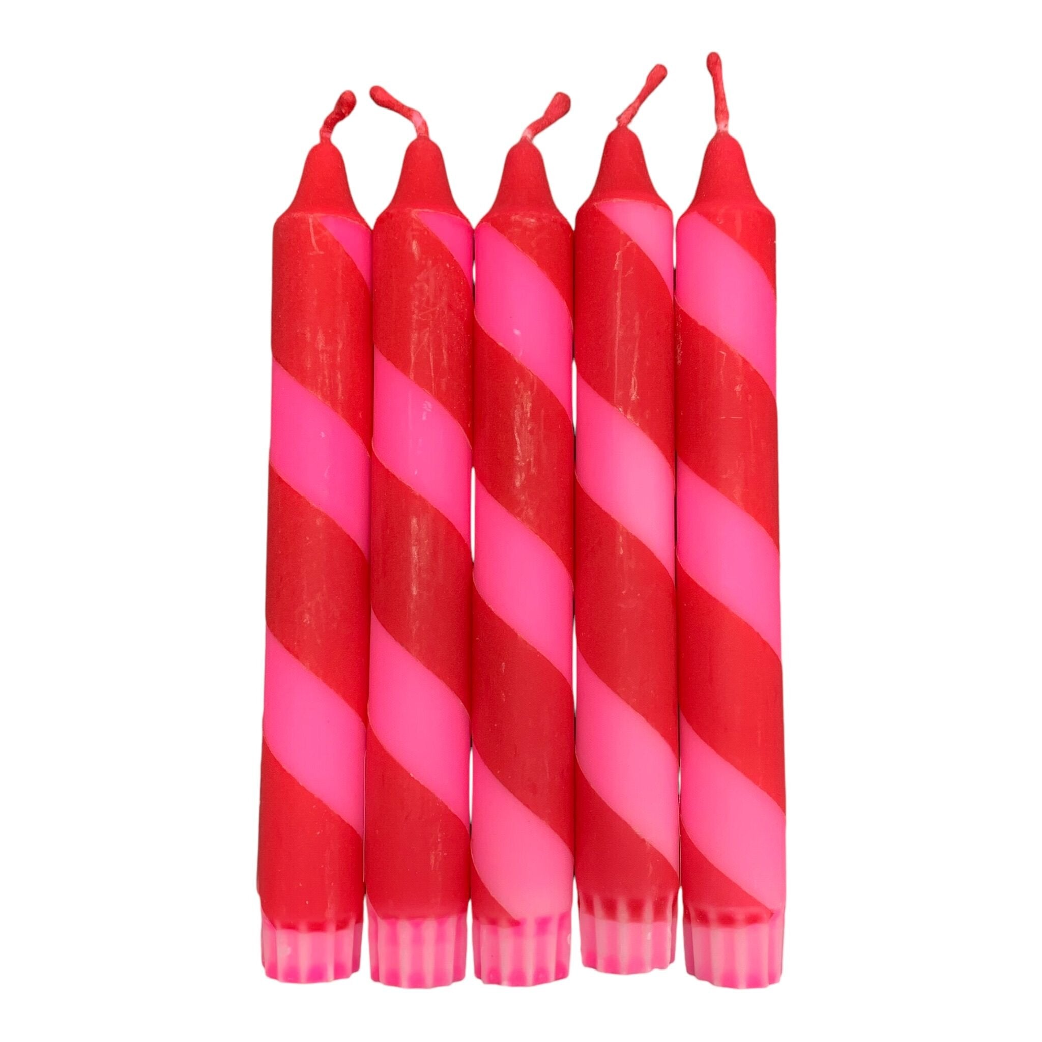 A row of 5 handmade dinner candles in bright pink and red diagonal stripes.