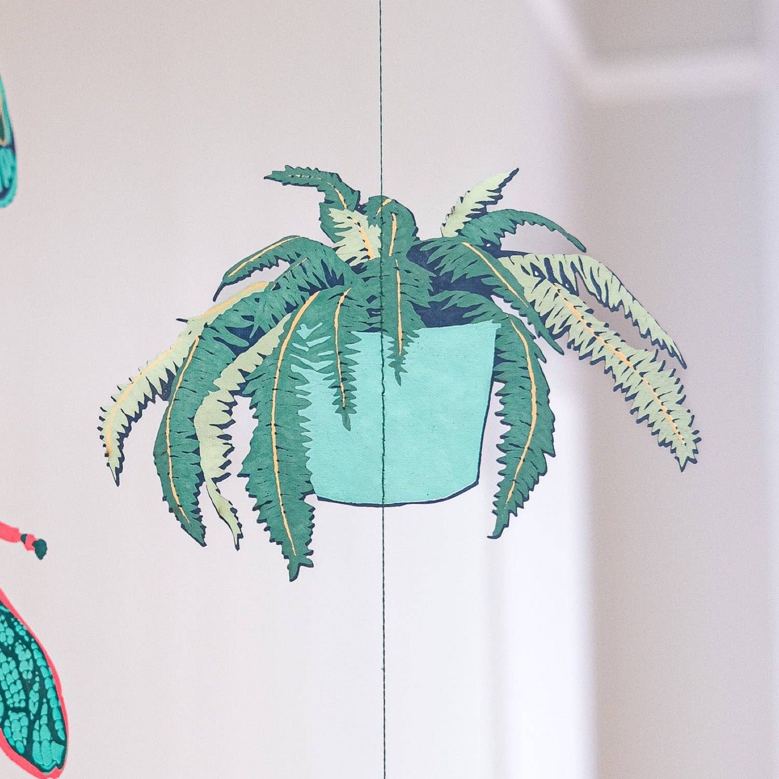 A house plant from a vertical paper garland in shades of green and mustard.