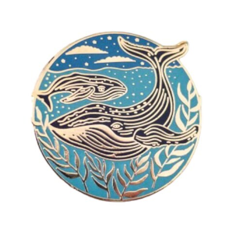 A circular enamel pin badge featuring a mother whale and her calf swimming in the sea at night, with a blue background and stars.