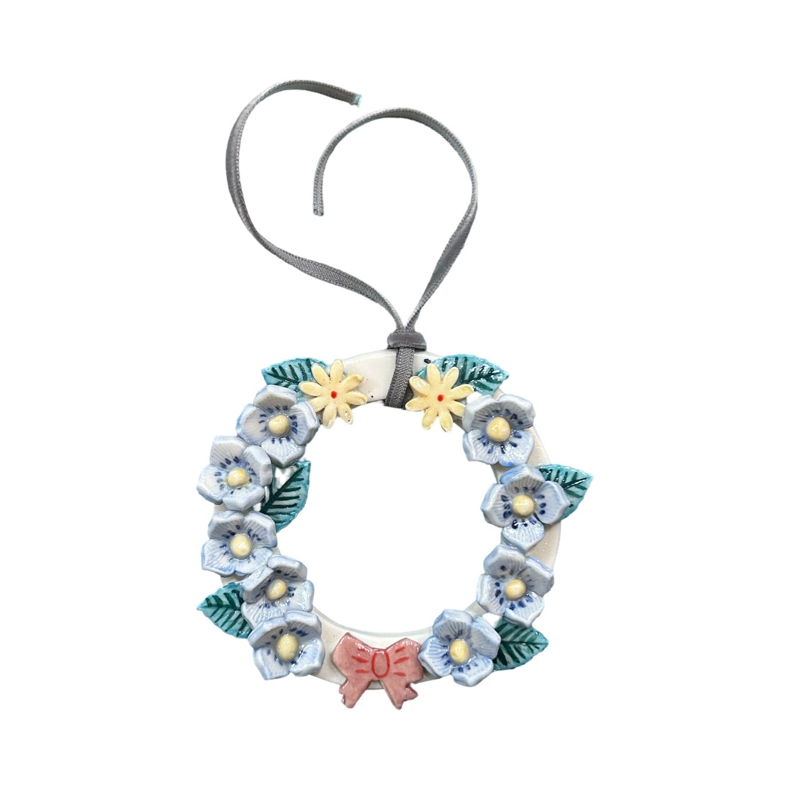 Floral wreath with blue and white flowers, green leaves, and a pink bow on a white background.