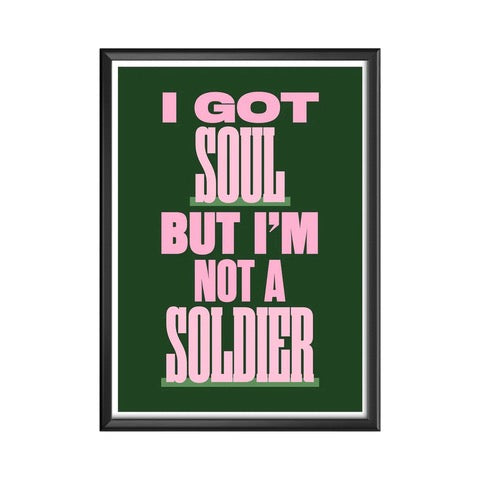Typography print of the lyric 'I Got Soul but I'm not a Soldier' from the song All These Things That I've Done by The Killers. The text is written in pink uppercase lettering against a deep green background with an off-white border.