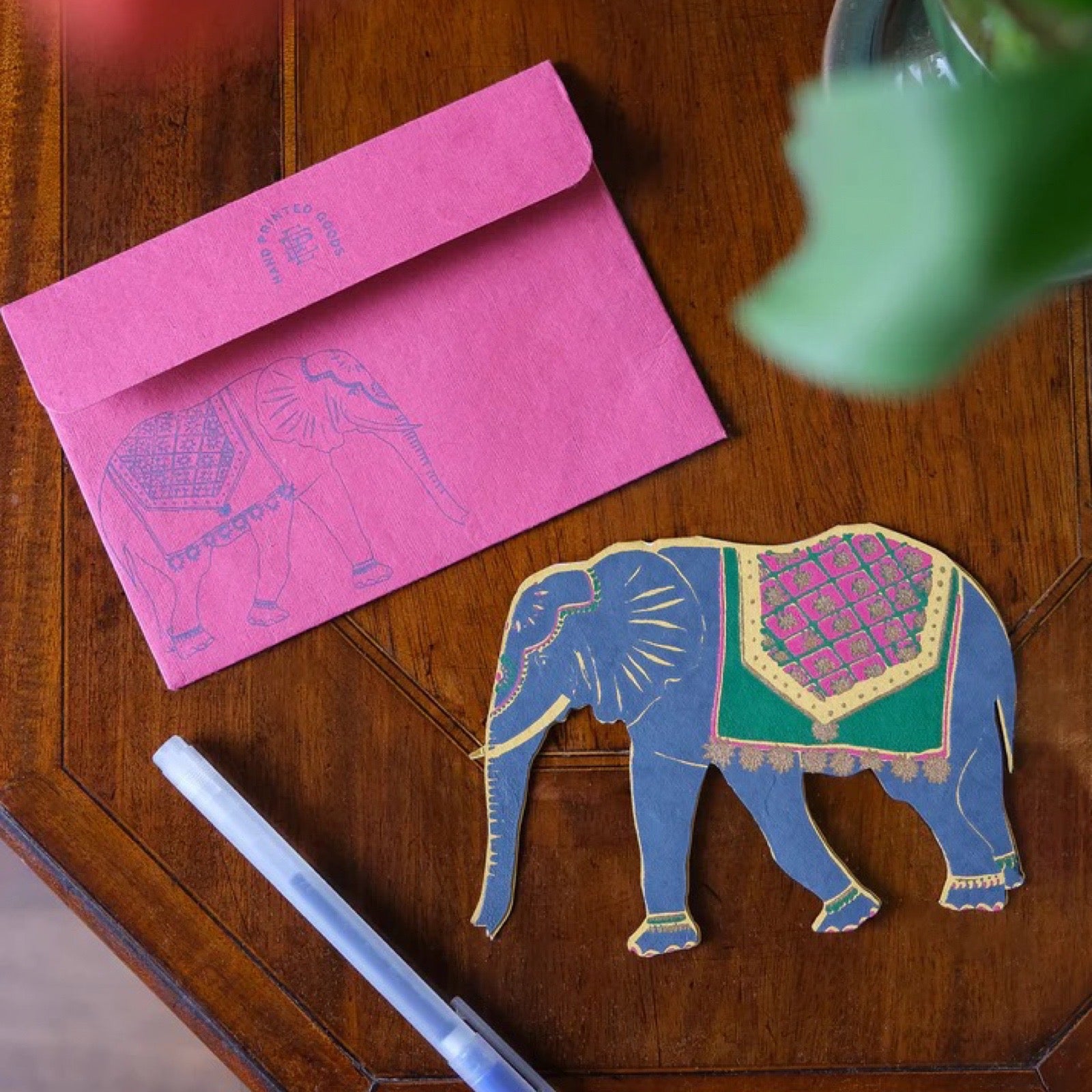 Decorative elephant cutout with pink and blue colours on a wooden surface.