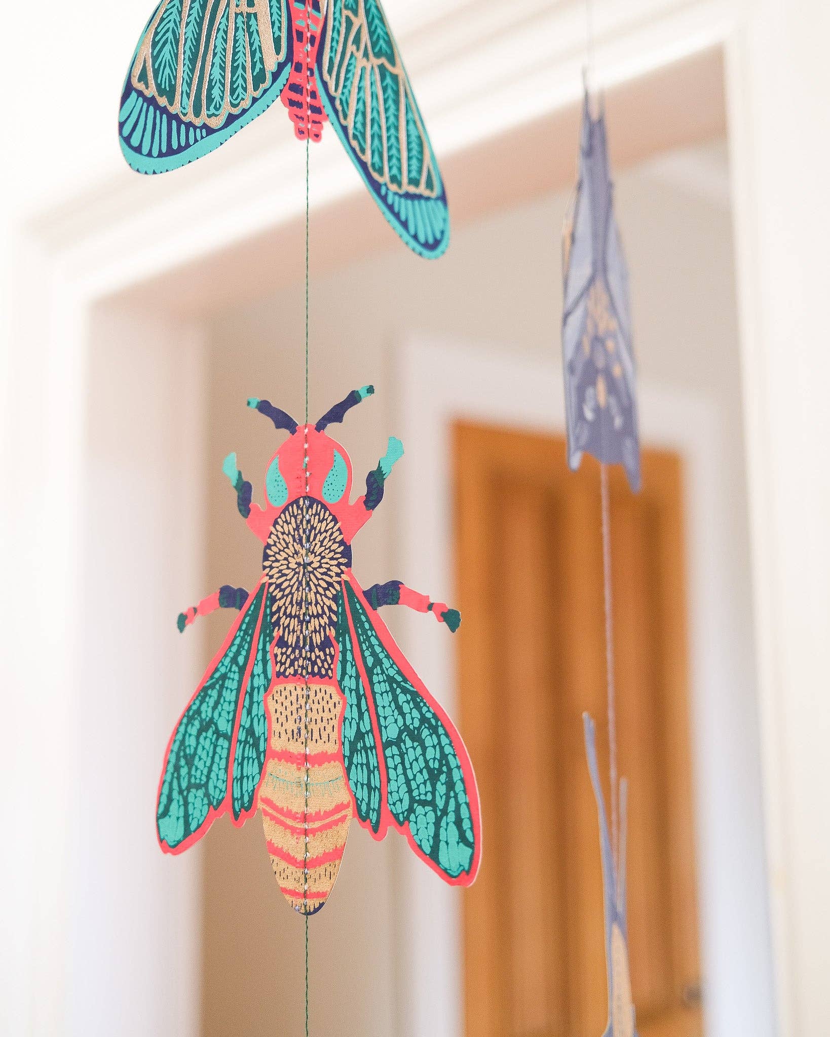 Colourful insect-shaped decorations hanging against a neutral background.