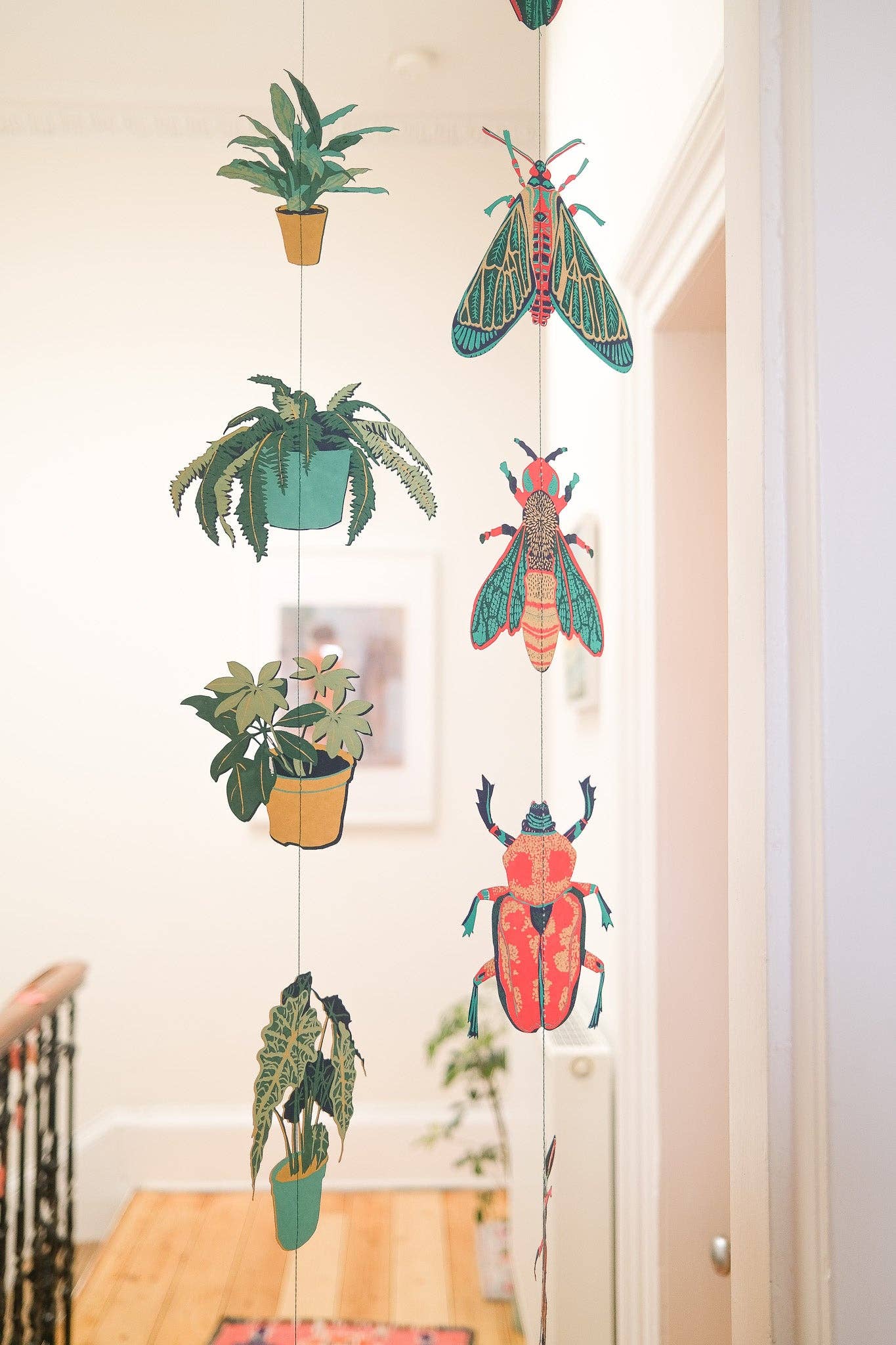 Decorative string with plants and insects hanging indoors.