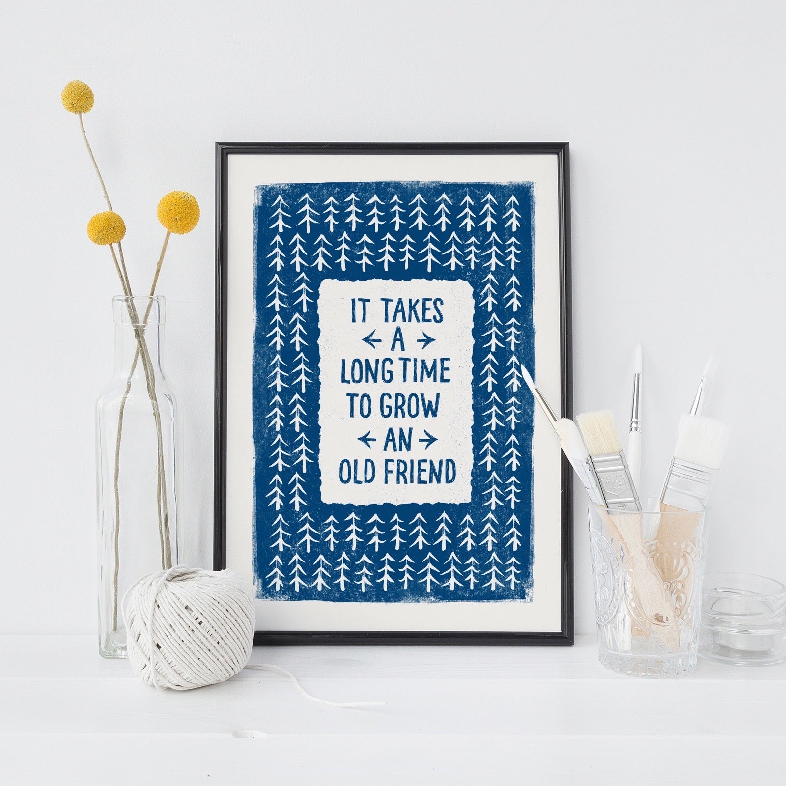 Framed print with motivational quote on a white surface with decorative items.