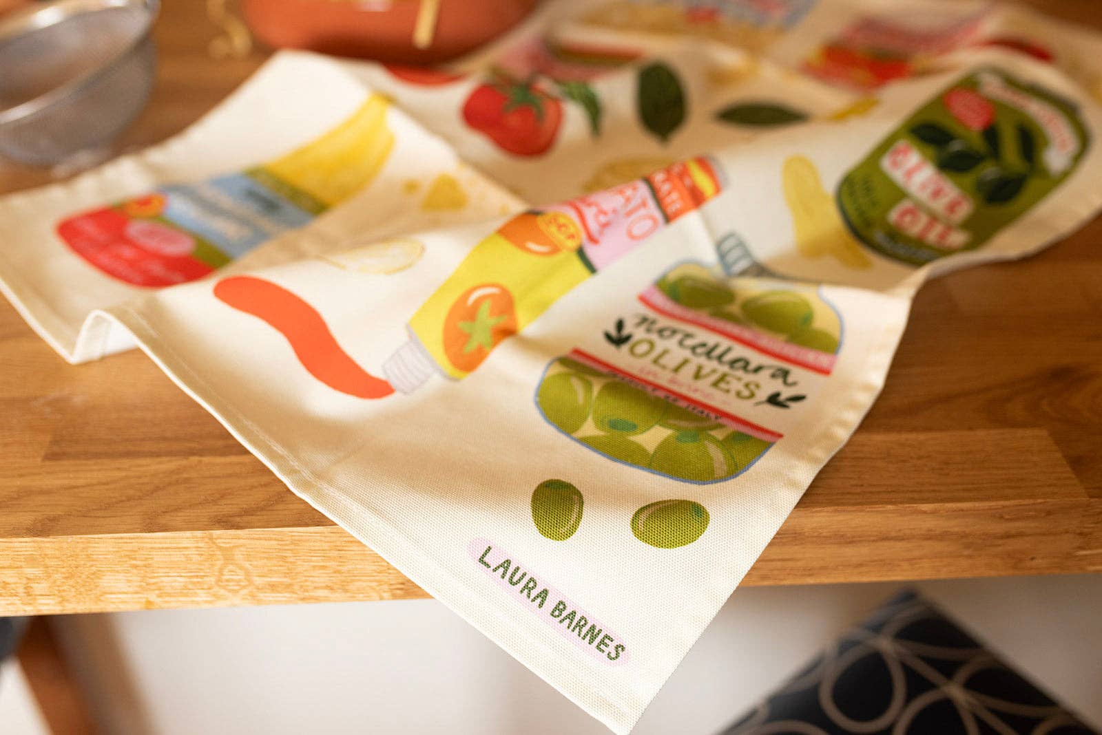 Packaging with illustrations of olives and text on a wooden surface.