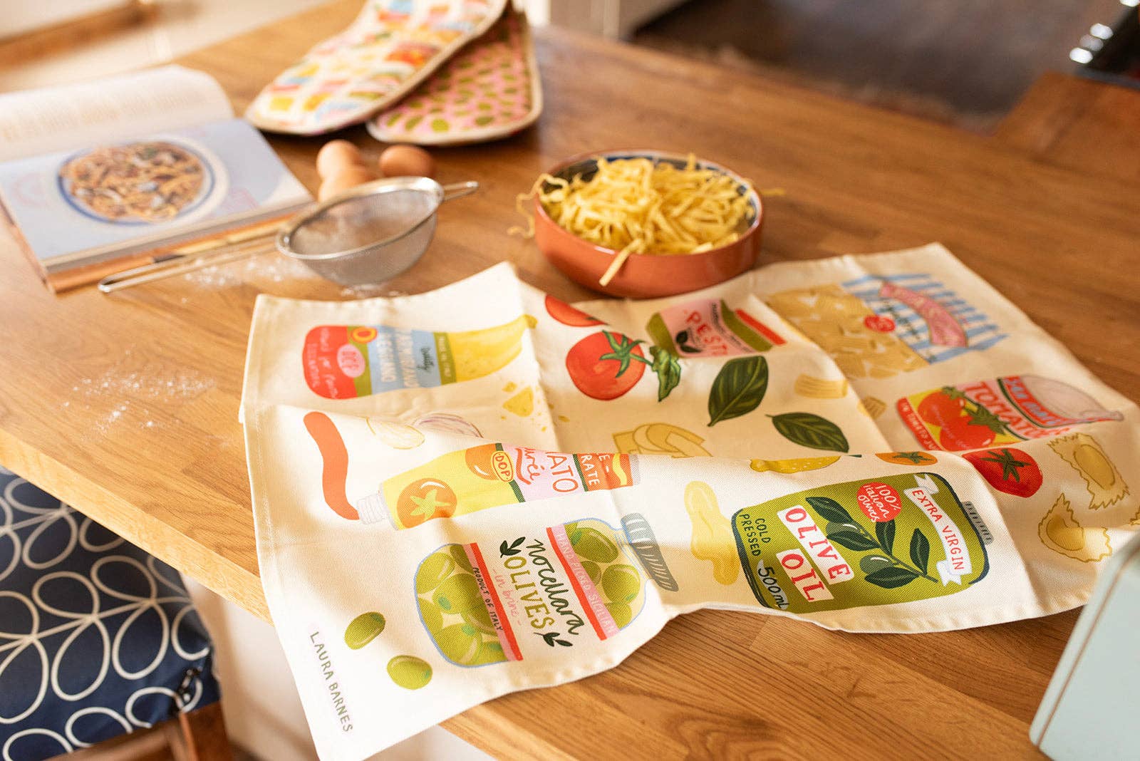 Tea towel with food-themed design on a wooden table.