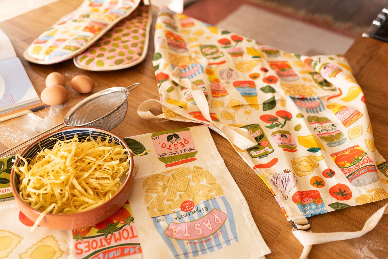Colourful kitchen towels with food-themed designs on a wooden table.
