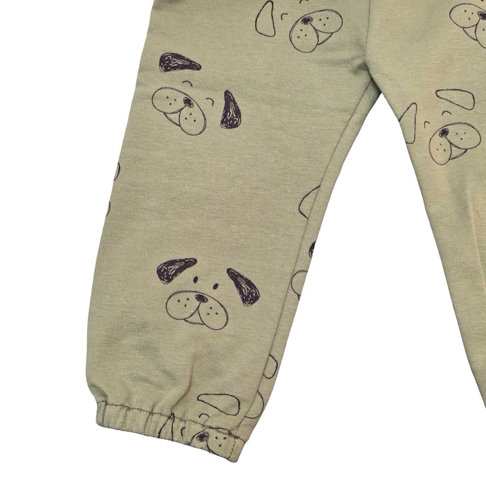 Green baby pants with dog face pattern on a white background.