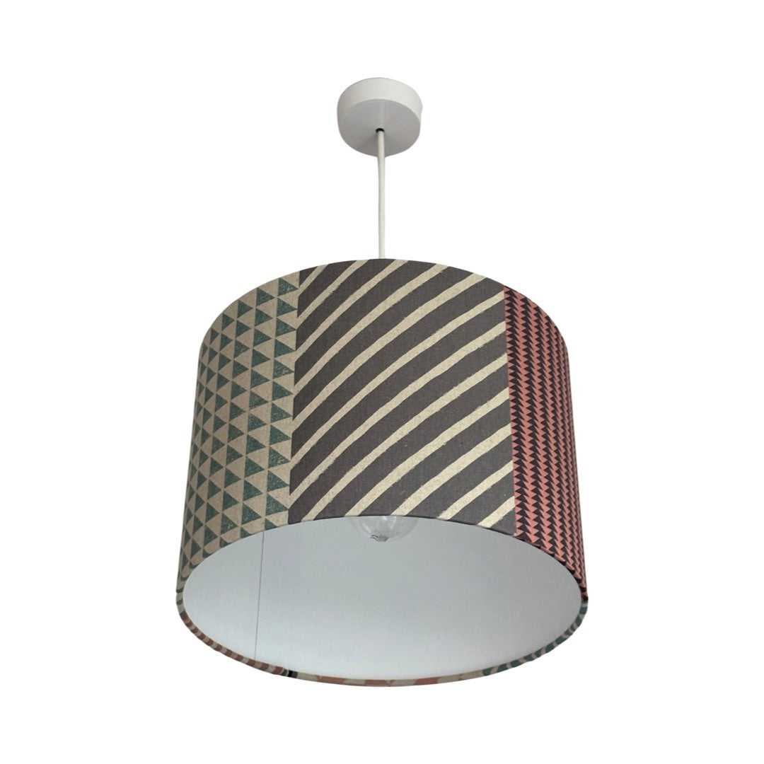 Handmade drum lampshade in panels of pink, grey, navy and cream geometric designs.