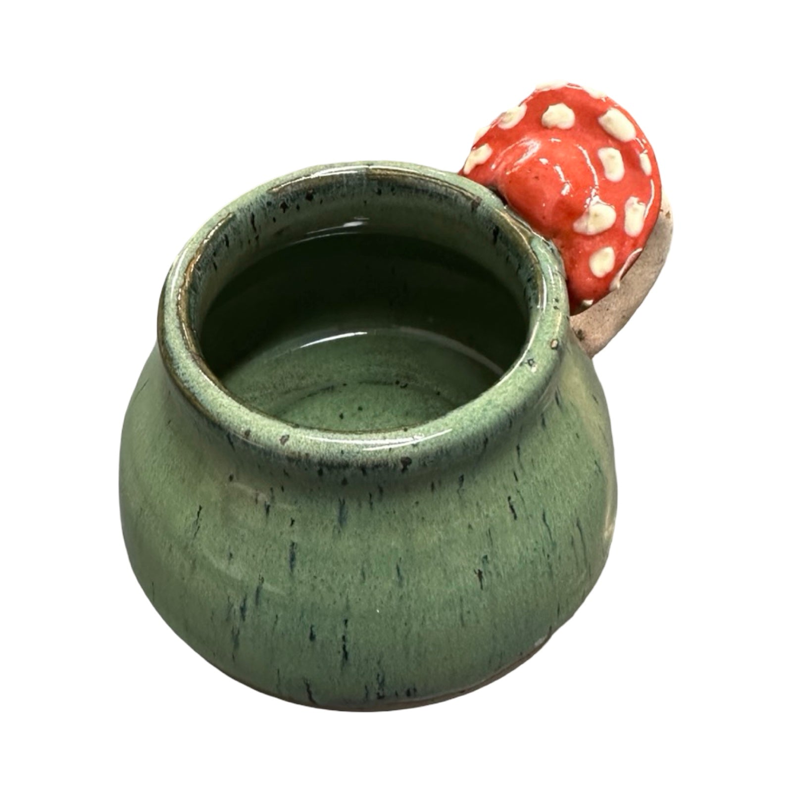 Green ceramic mug with a red mushroom-shaped handle on a white background.
