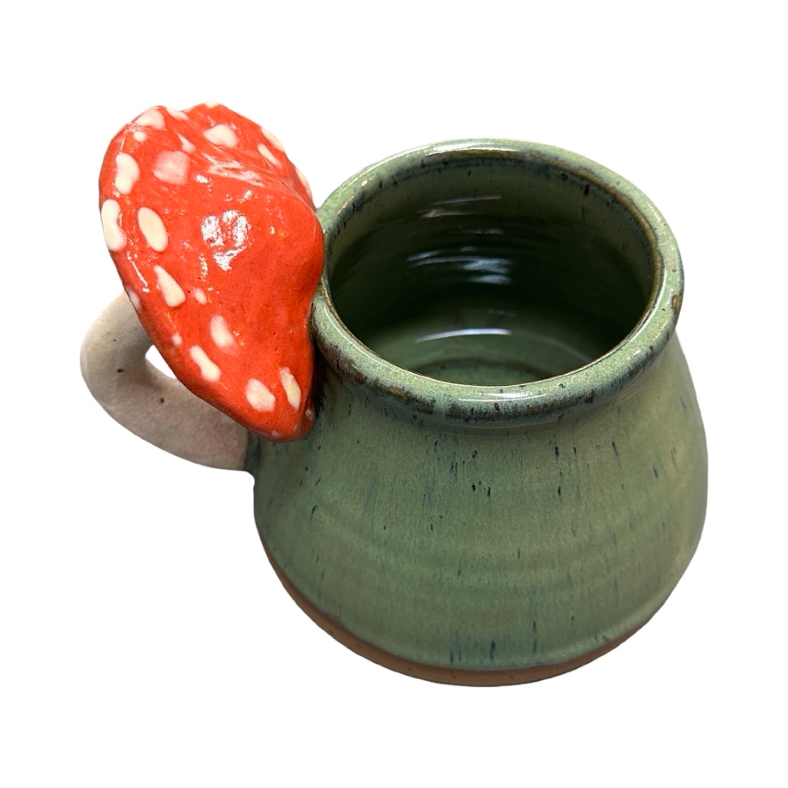 Green ceramic mug with a red mushroom-shaped handle on a white background.