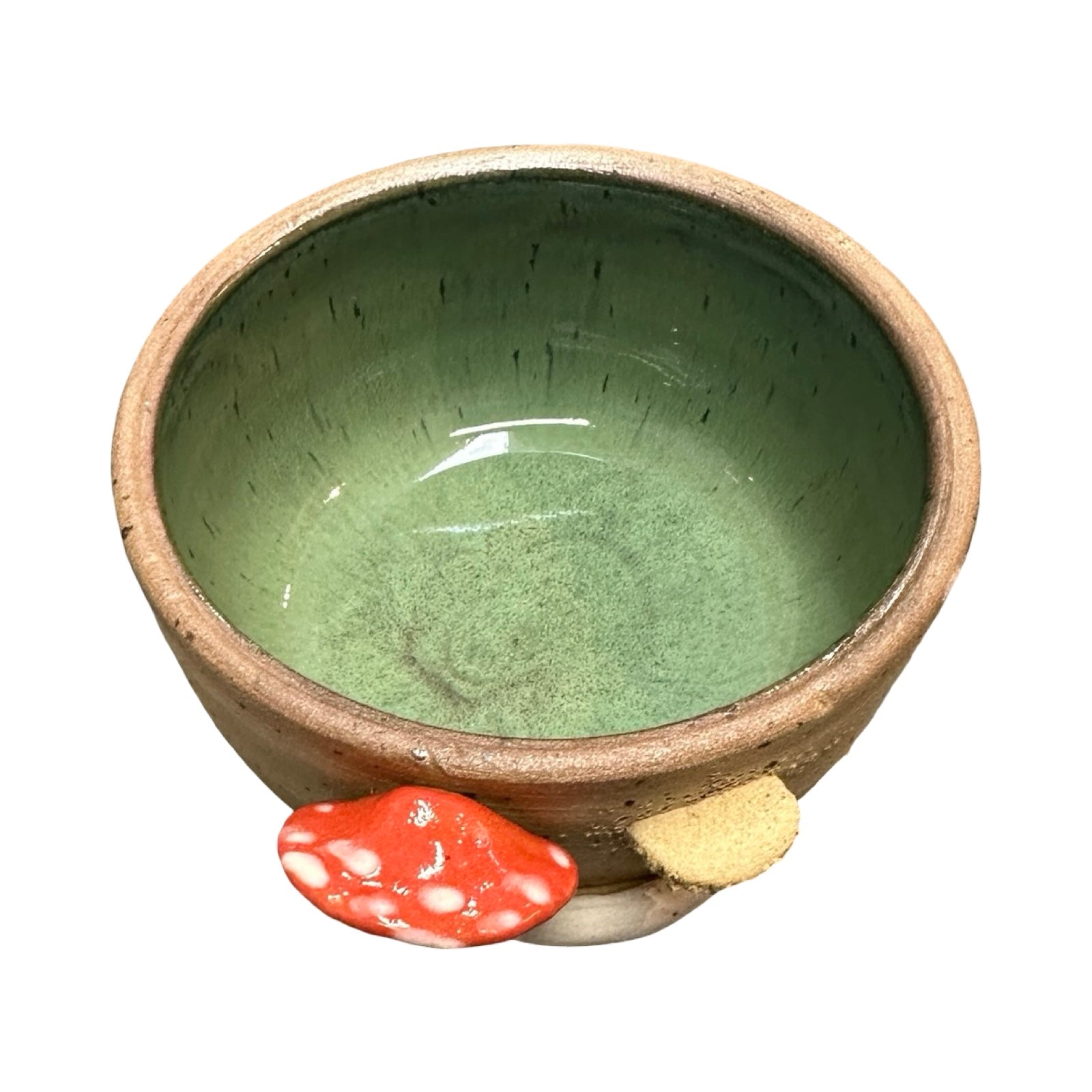Ceramic trinket dish with a textured green interior and beige exterior, with a mushroom design on the outside on a white background.