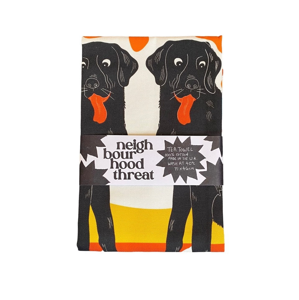 Tea towel of two black labrador dogs sitting on a red floral blanket under the moon.