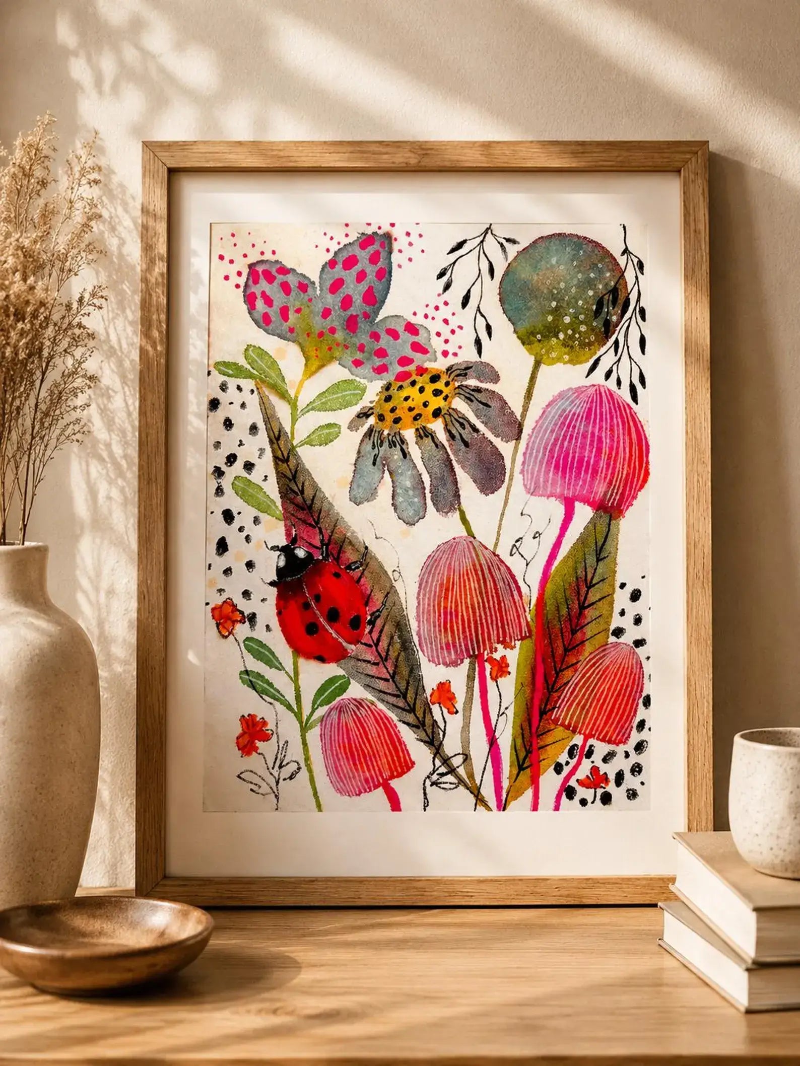 Framed colourful floral artwork on a wall with decor items below.