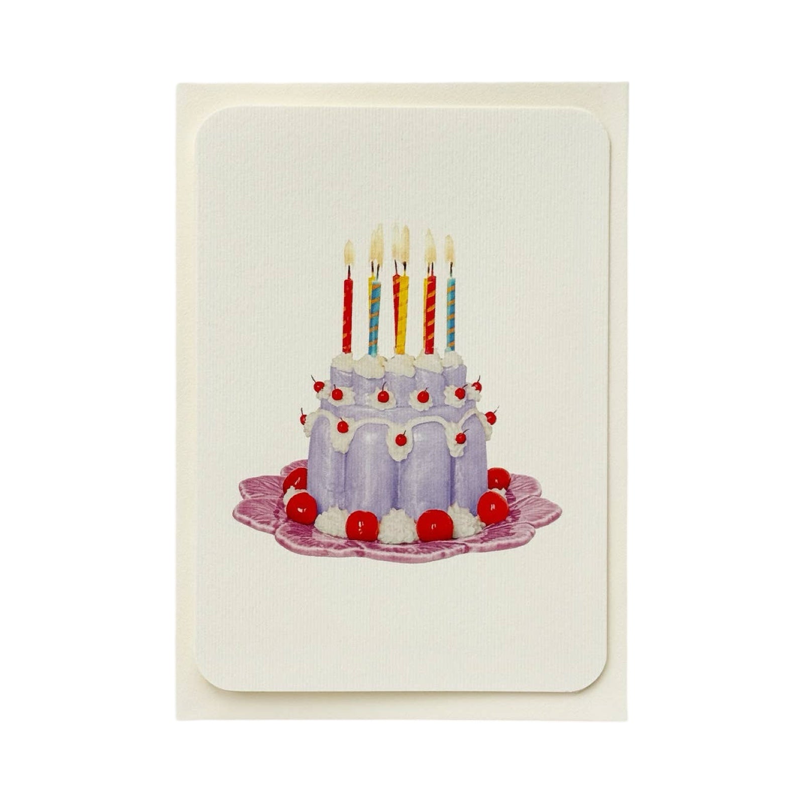 A cream coloured birthday card with a lavender coloured blancmange with cherries and cream and colourful candles  on the top, all on a pink plate.