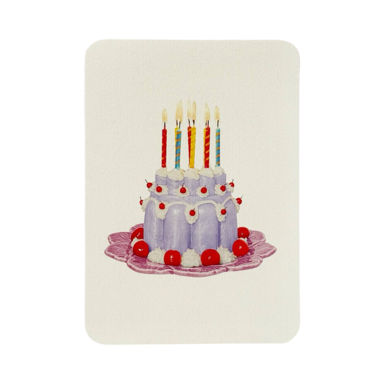 A cream coloured birthday card with a lavender coloured blancmange with cherries and cream and colourful candles  on the top, all on a pink plate.