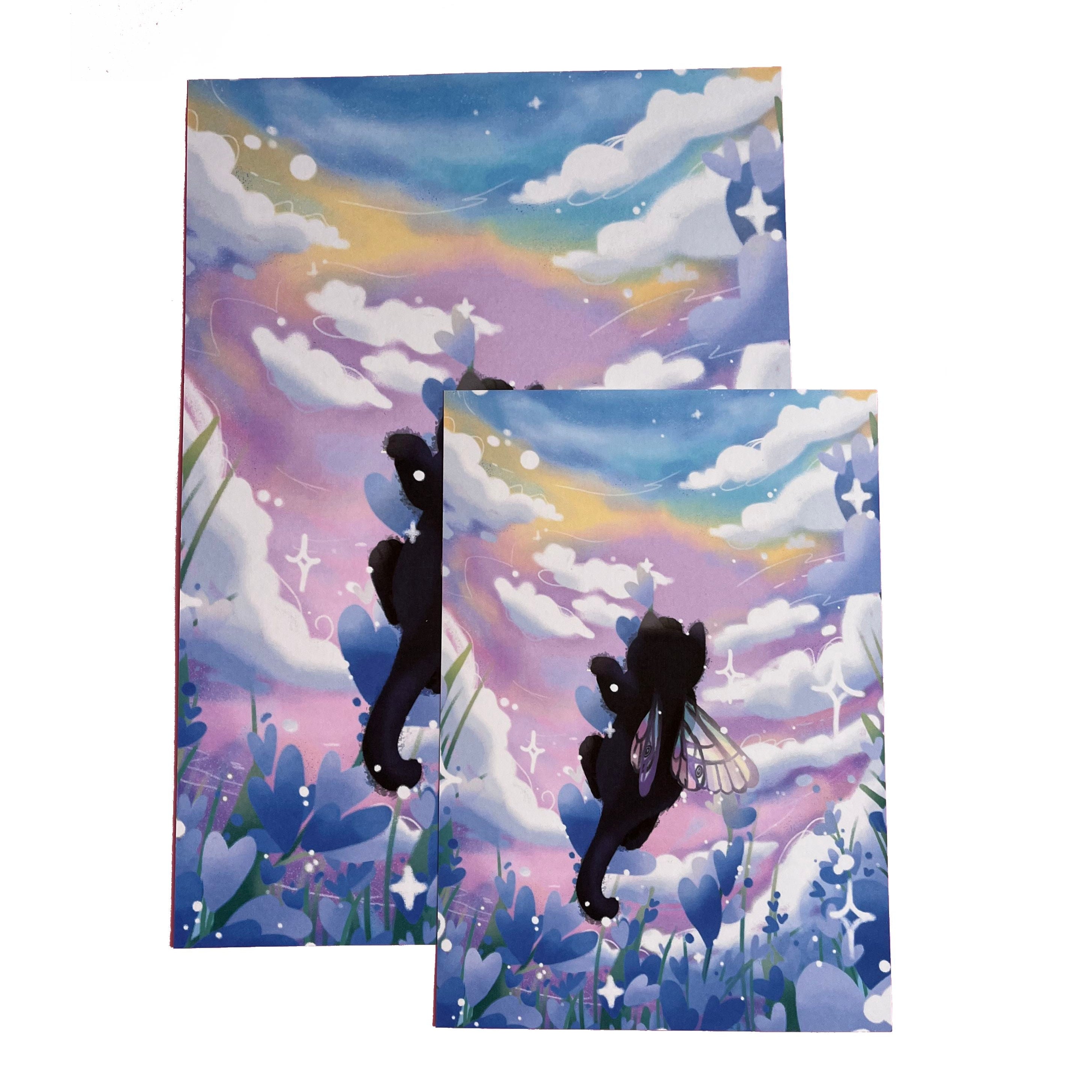 Photo of two art prints atop each other in A4 and A5 size, of an illustration of a flower fairy black cat with rainbow fairy wings, climbin lavender in a lavender field.