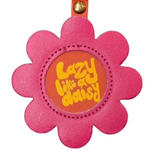 Pink flower-shaped keychain with 'Lazy like a daisy' text on an orange background.