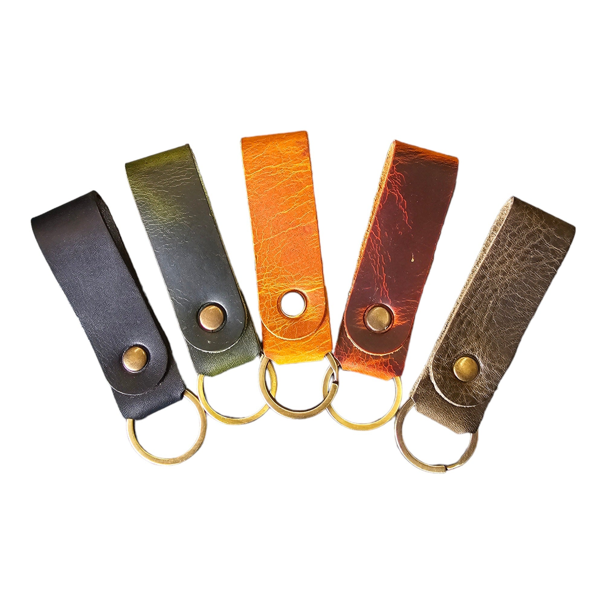 A collection of handmade leather keychains in various colors including black, brown, gray, green, and tan, each with a stamp of the Workshop After 6 logo and a metal ring for keys.