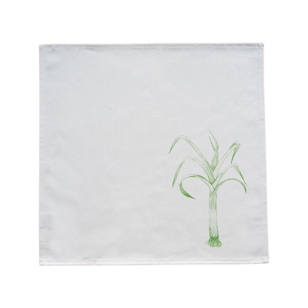 Cream cotton napkin with a green leek rolled on a plate.