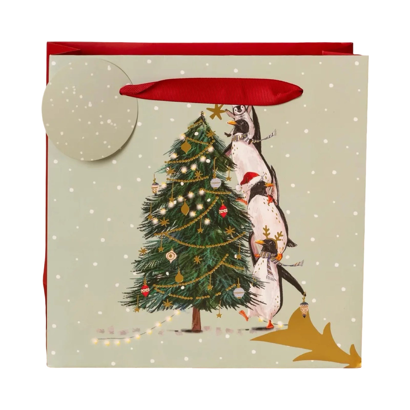 Christmas gift bag with a penguin decorating a Christmas tree on a light green background.
