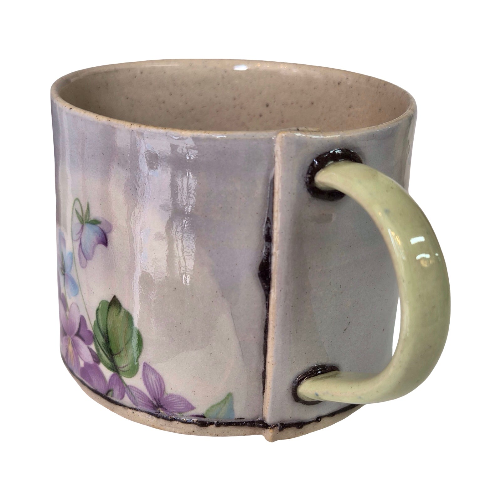 Ceramic mug with floral design and green handle on a white background.