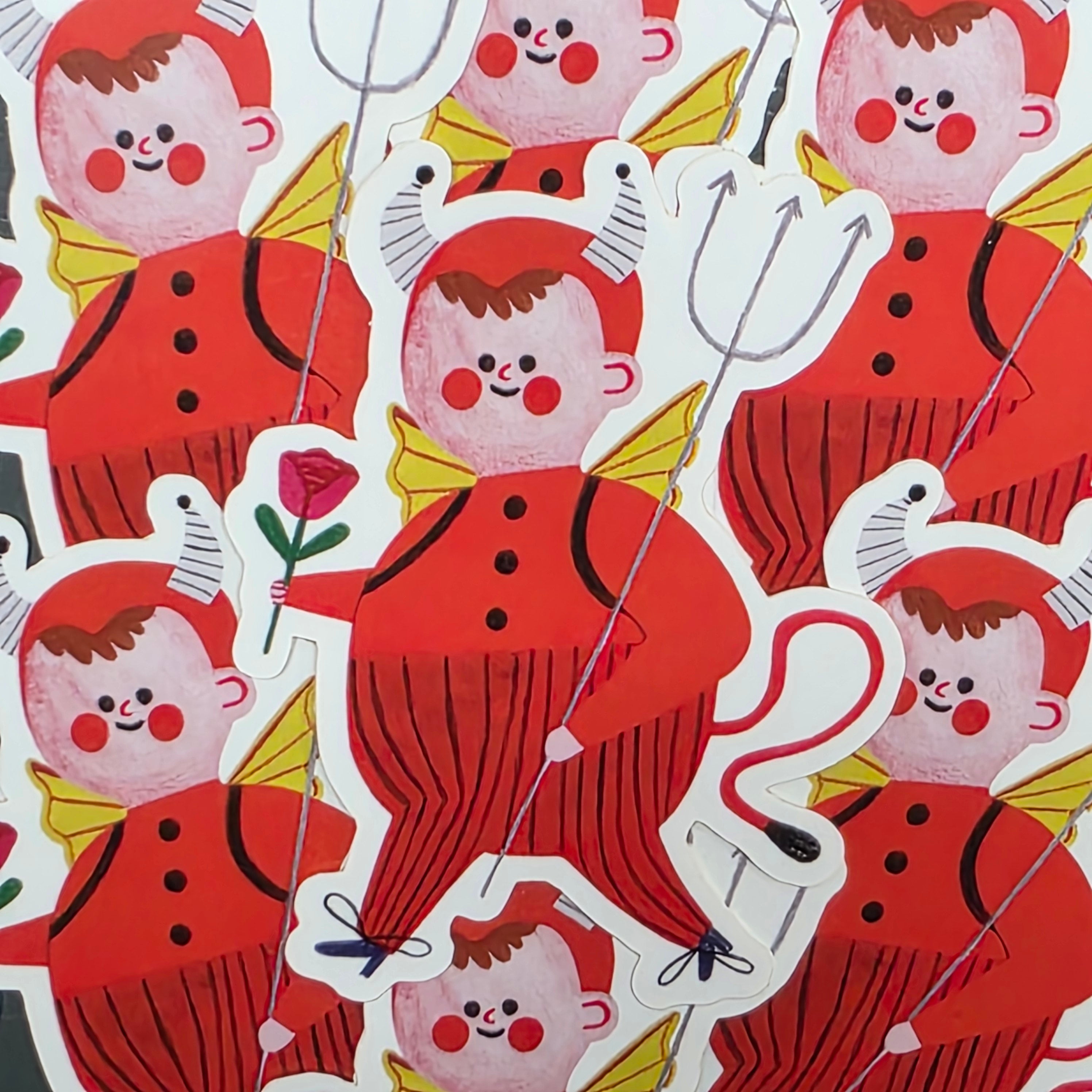This vinyl sticker features a little red devil with grey horns, gold wings and carrying a red rose.