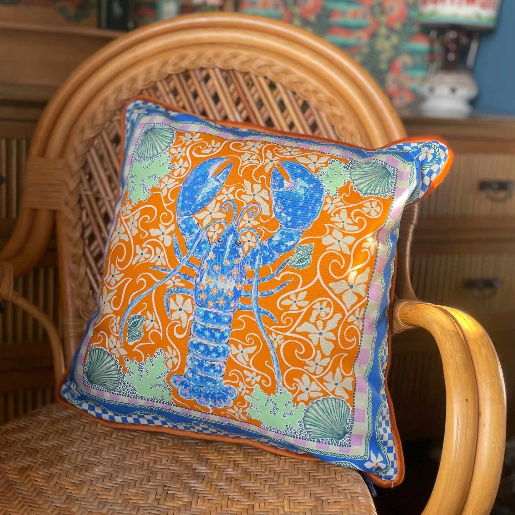 Decorative cushion with a lobster design on a wicker chair.