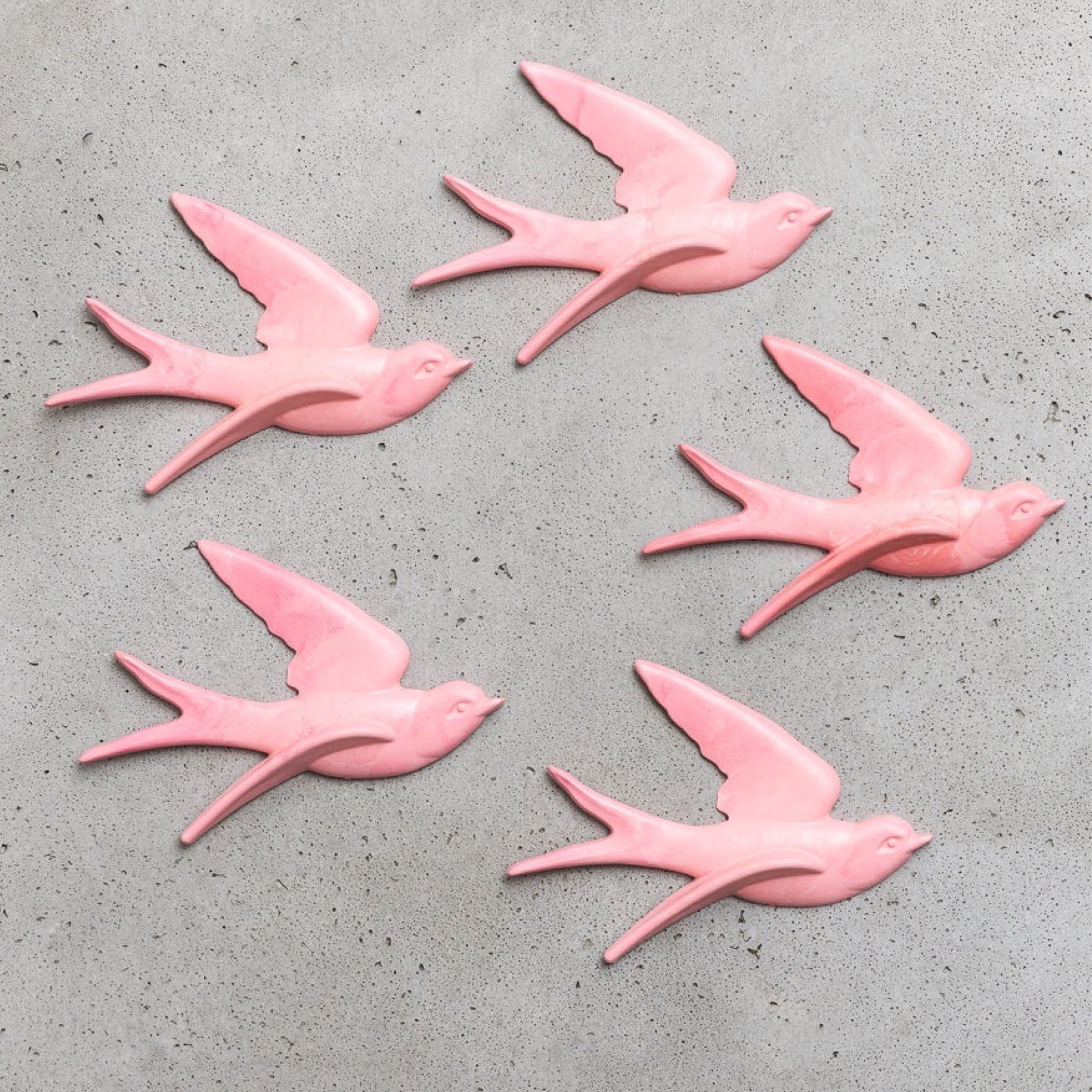 Five pink swallows on a grey background.