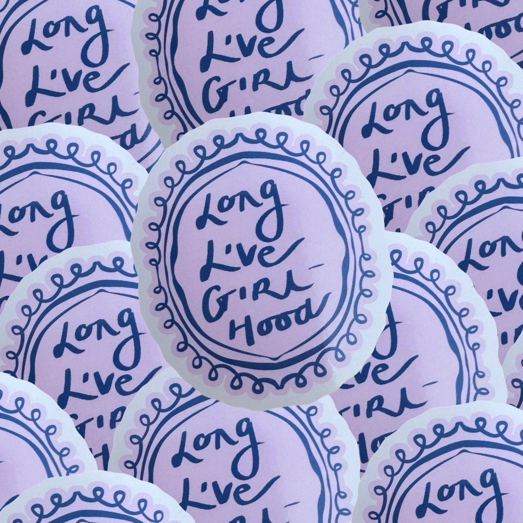 A close-up of multiple round white stickers with the text 'Long Live Girl Hood' in dark blue on a purple background and a scalloped boarder.