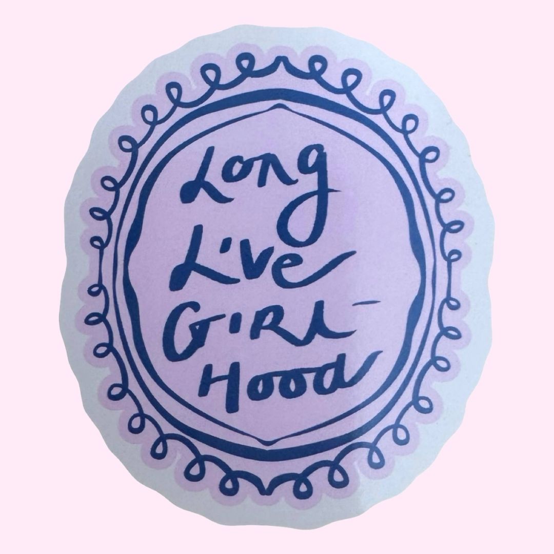 A round decorative sticker with a scalloped edge, featuring 'Long Live Girl Hood' dark blue text inside a decorative circular border, set against a solid pale pink background.