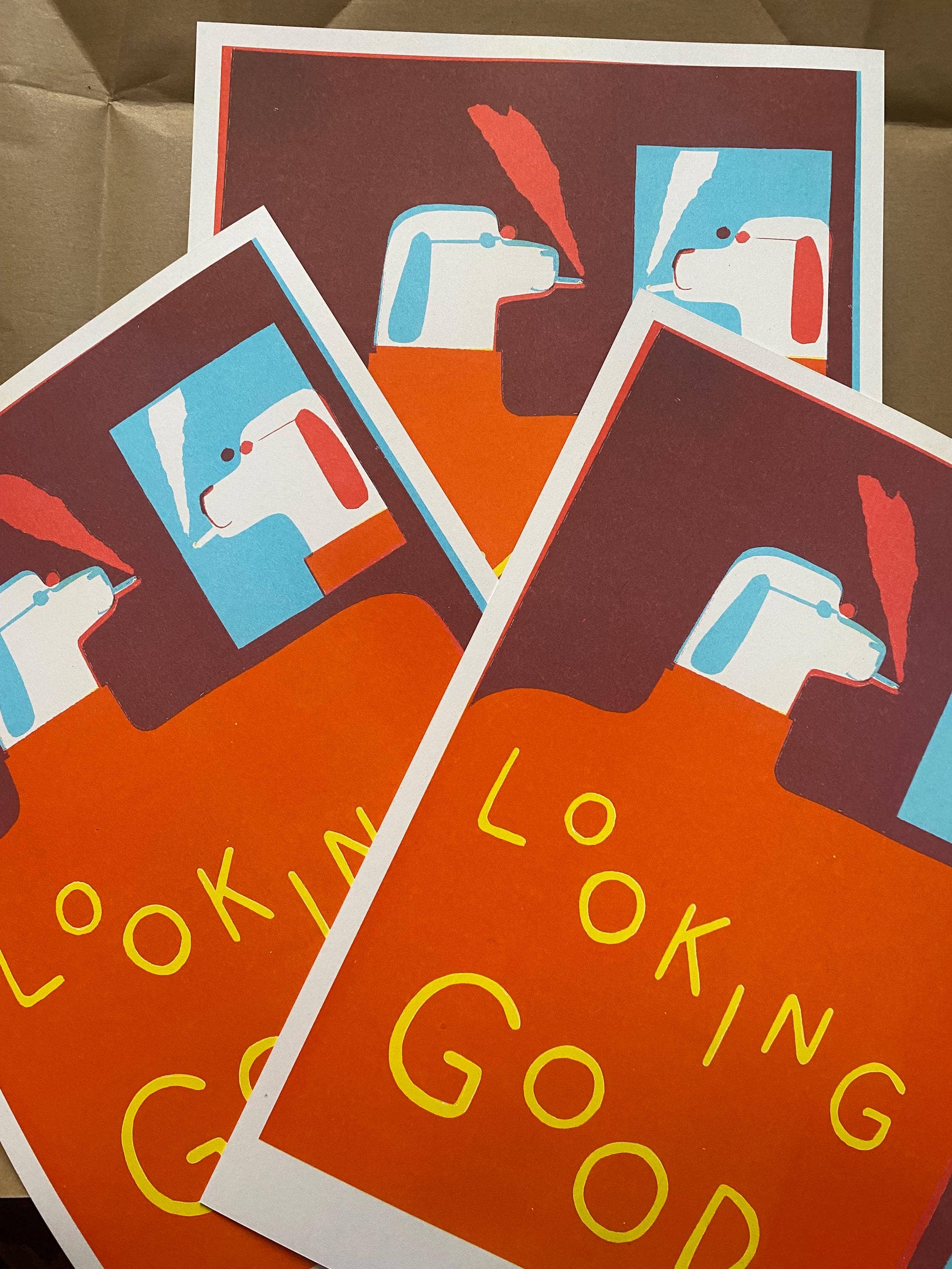 Three posters with a stylized dog illustration and text on a brown surface.