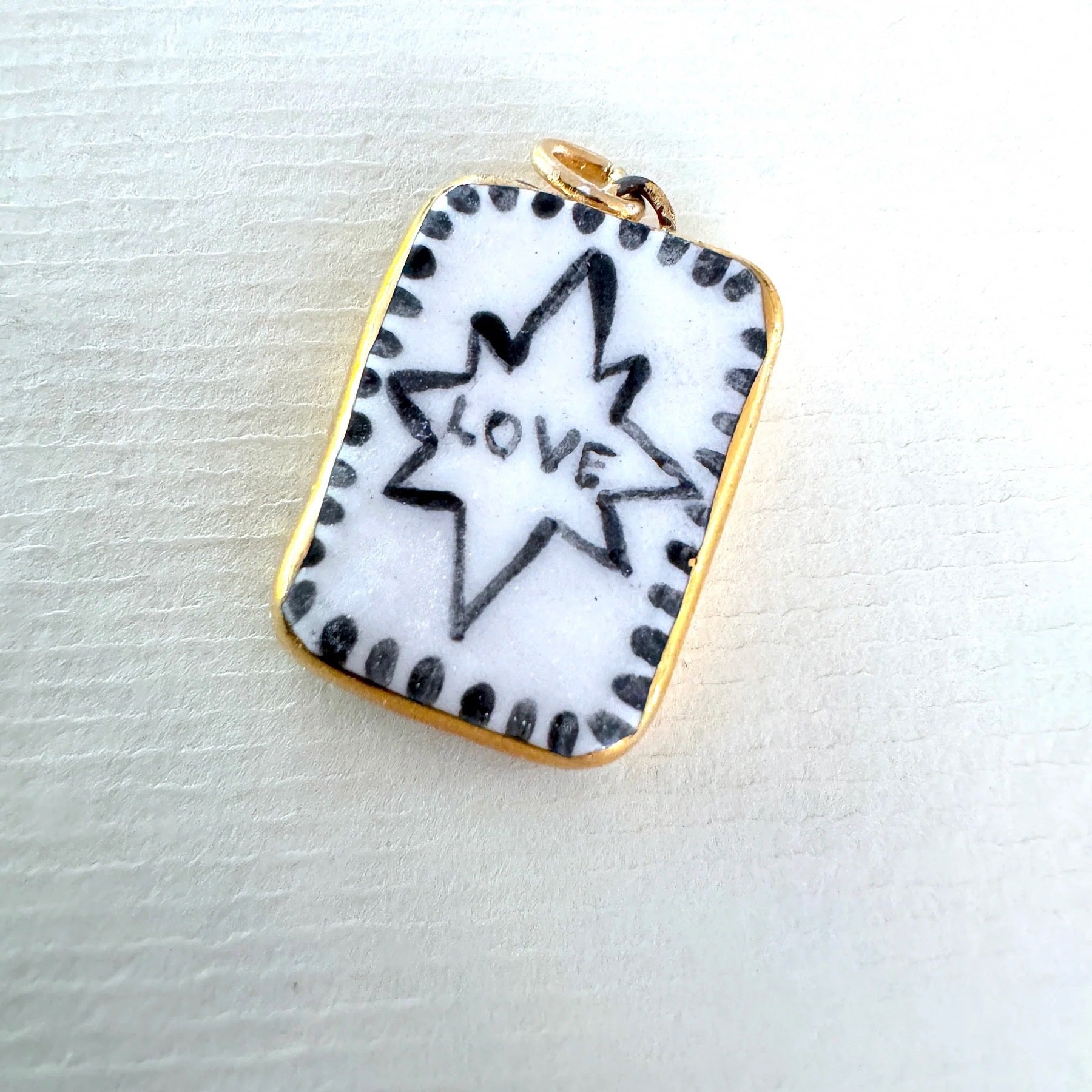 Pendant with star design and 'love' text on a white background.