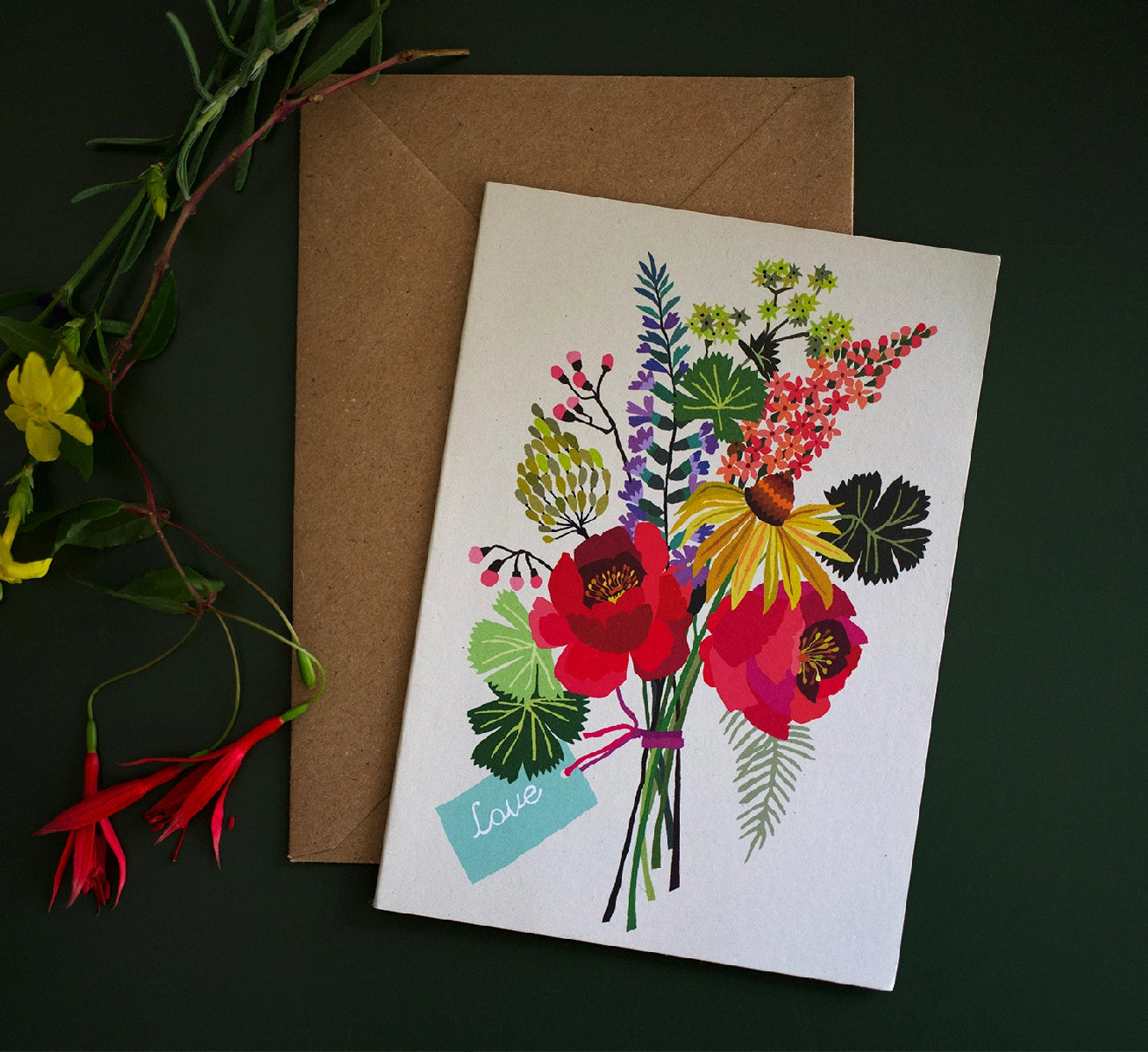 Greeting card with colourful floral design and brown envelope on a dark background.