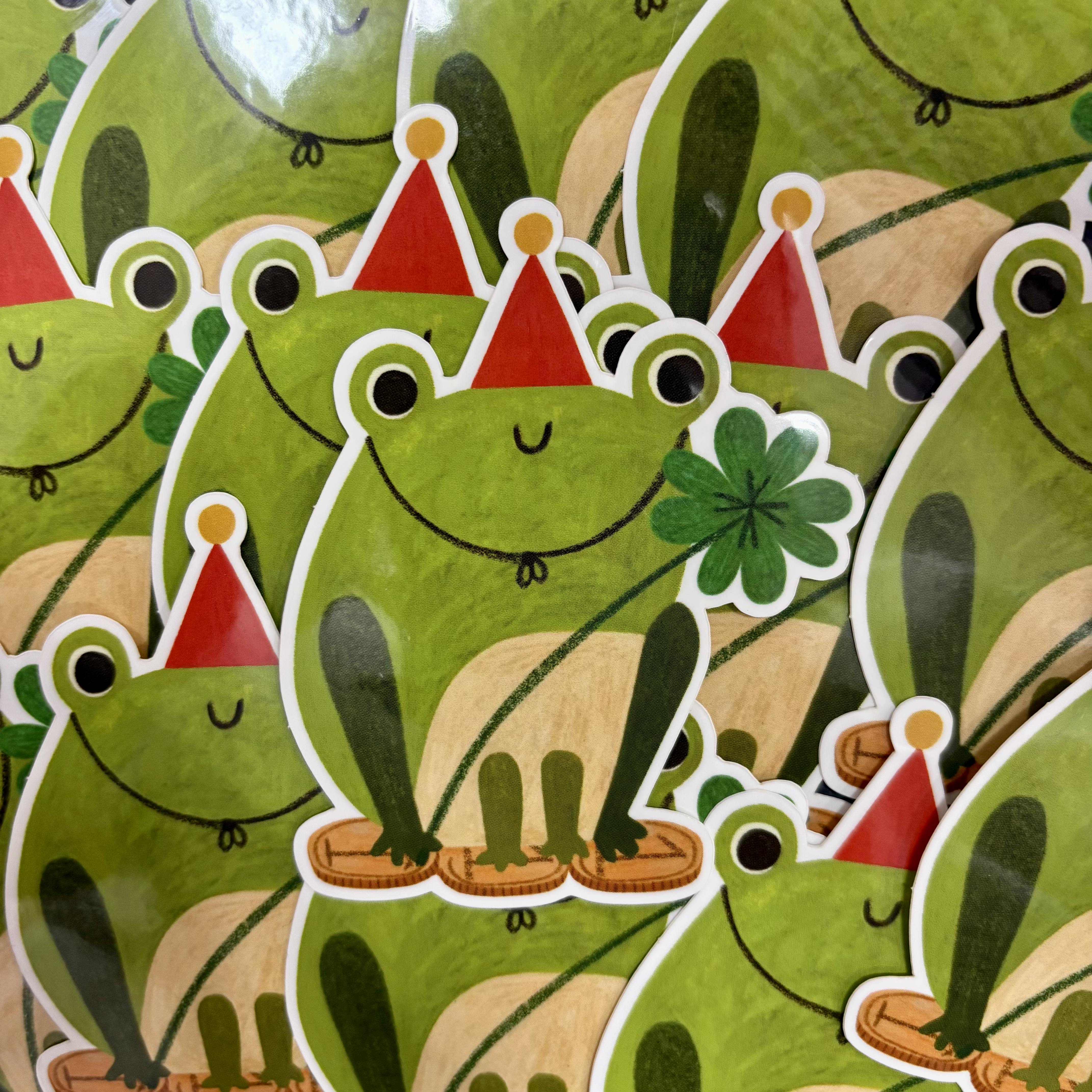 Stickers of green frogs with red hats and a four-leaf clover on a green background.