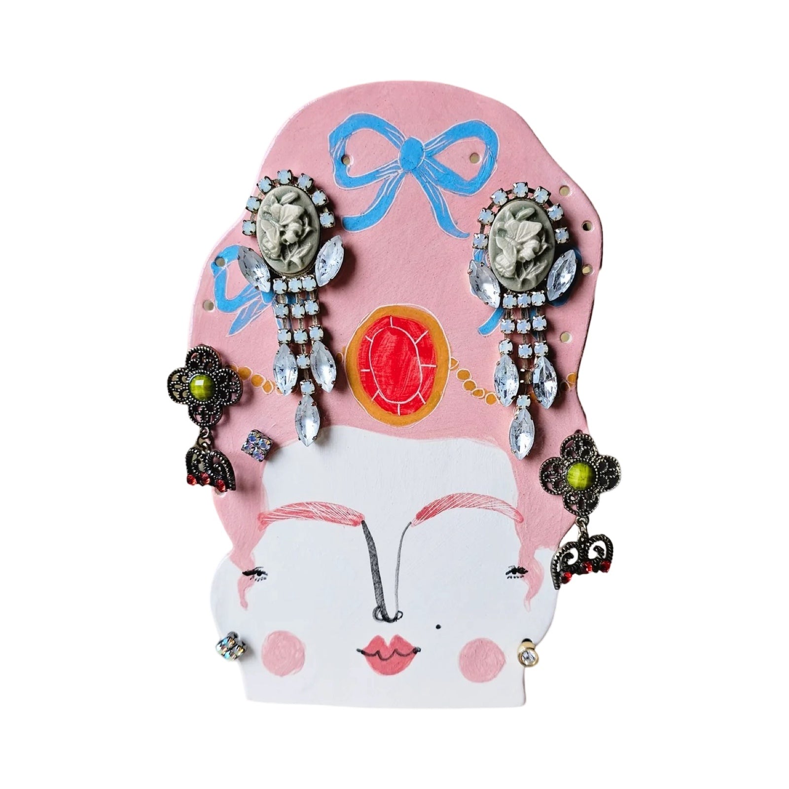 Handmade earring holder shaped like a lady's head wearing a huge pink wig with blue bows in it with h4 huge chinky earrings hanging from it.