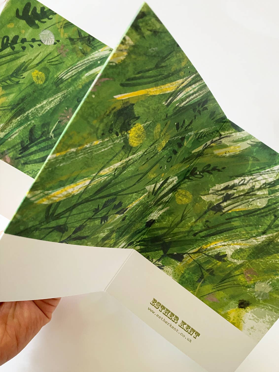 Hand holding a card with green floral design and 'Blossom Kent' branding.