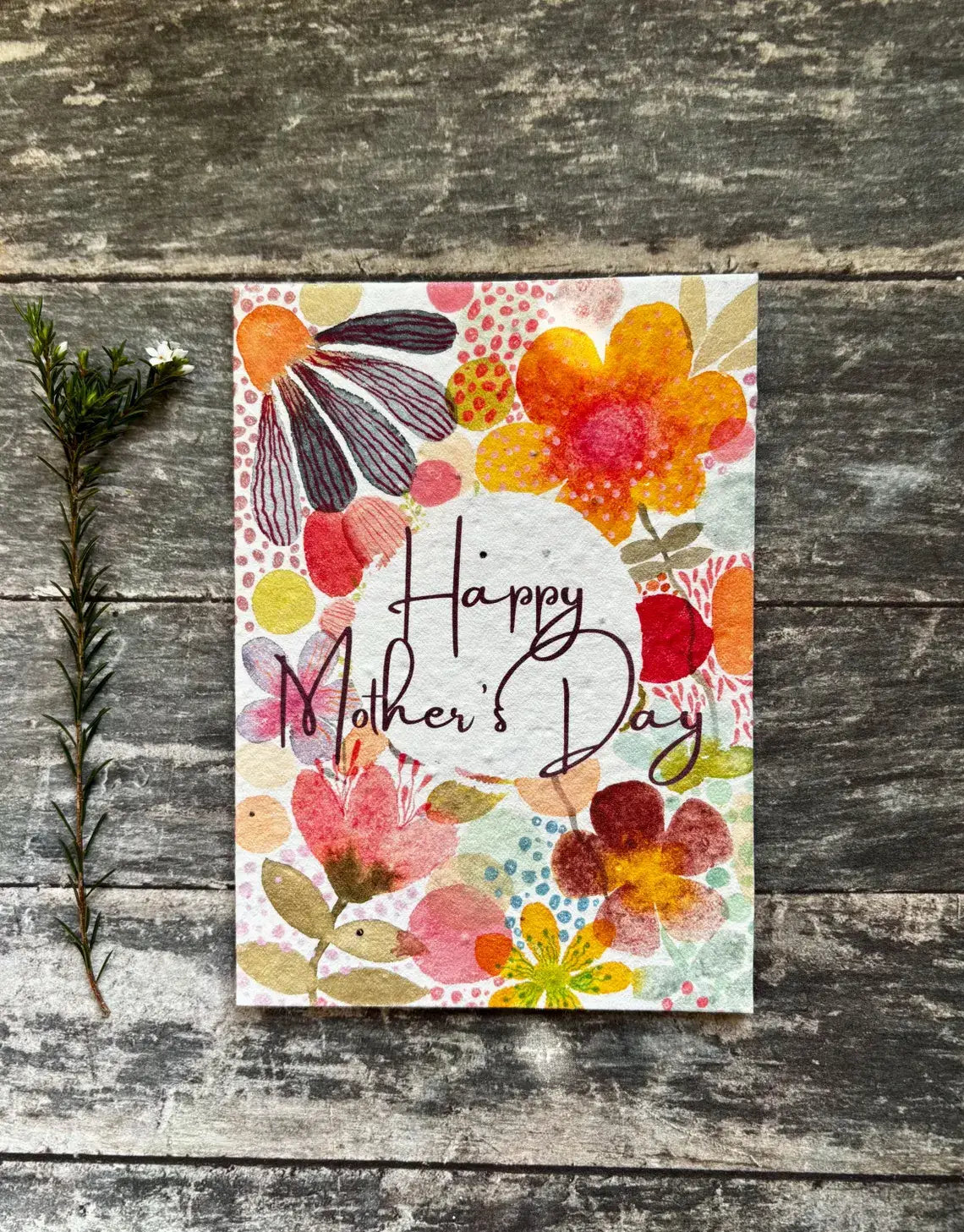 Colourful 'Happy Mother's Day' card with floral design on a wooden surface.