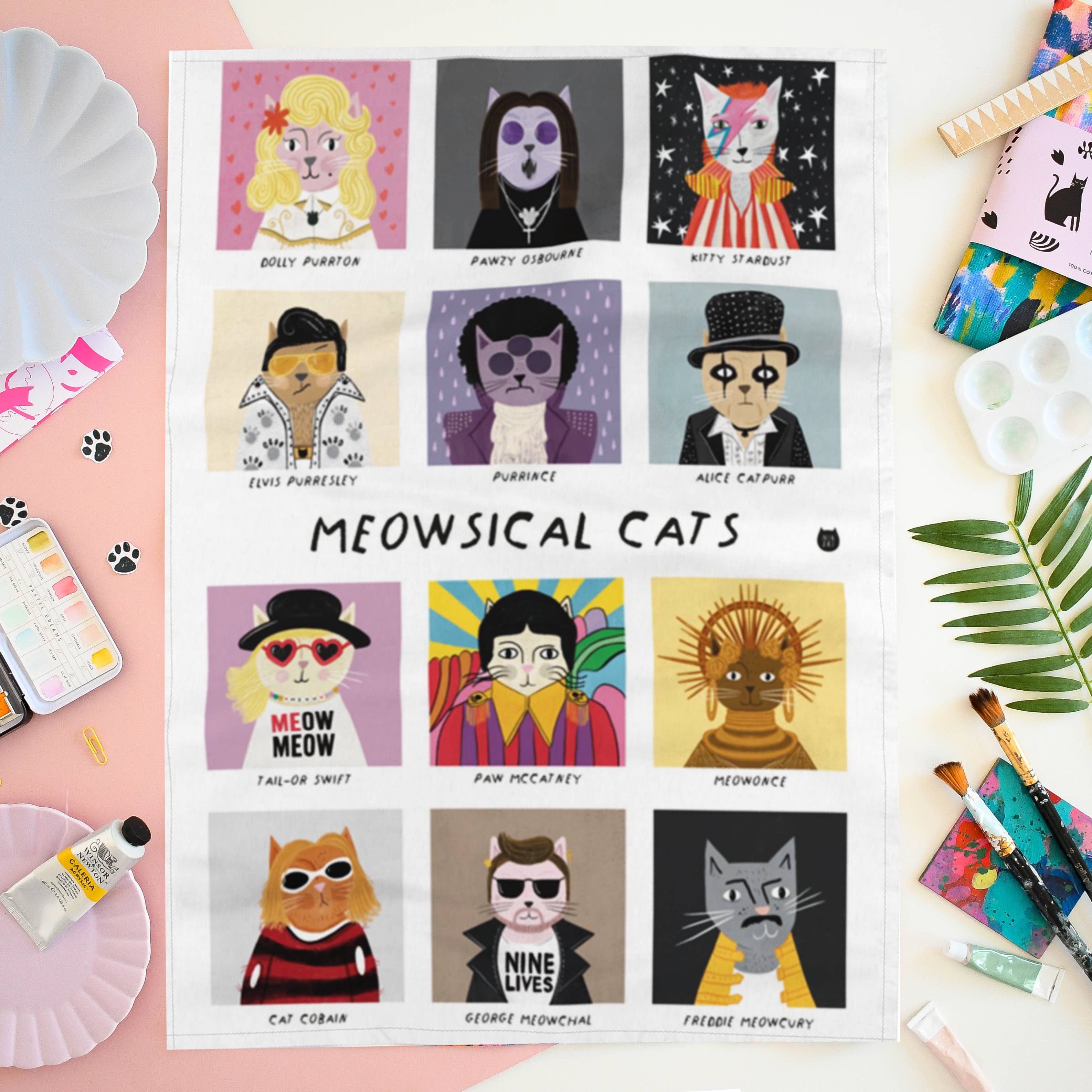 Tea towel of 'Meowsical Cats' with illustrated cats in various styles on a colourful background.