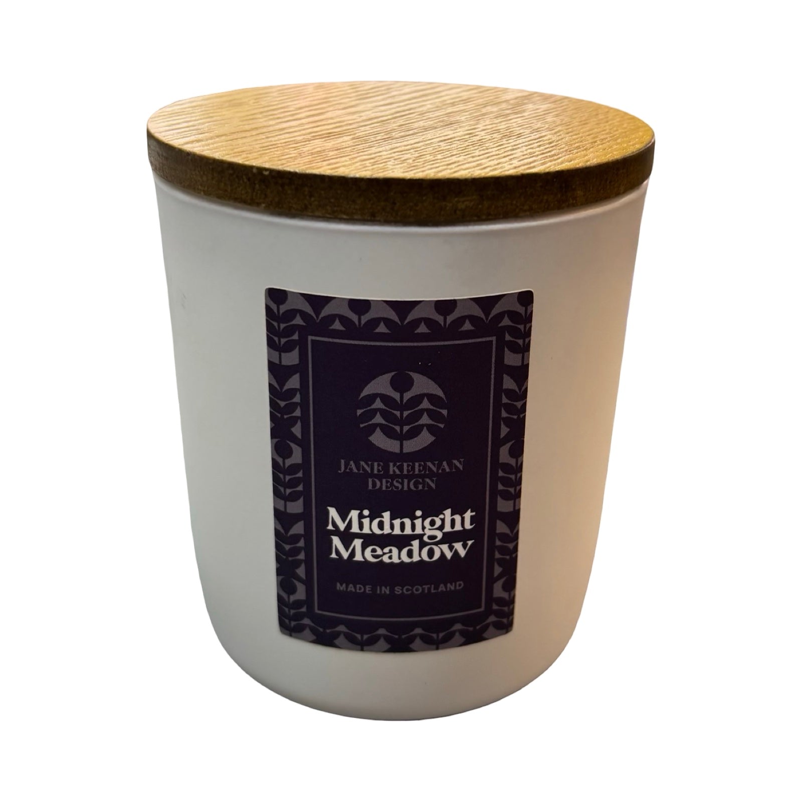 A white glass jar candle with a light brown wooden lid, featuring a dark navy label with the brand 'Jane Klenan Design' and scent name 'Midnight Meadow'.