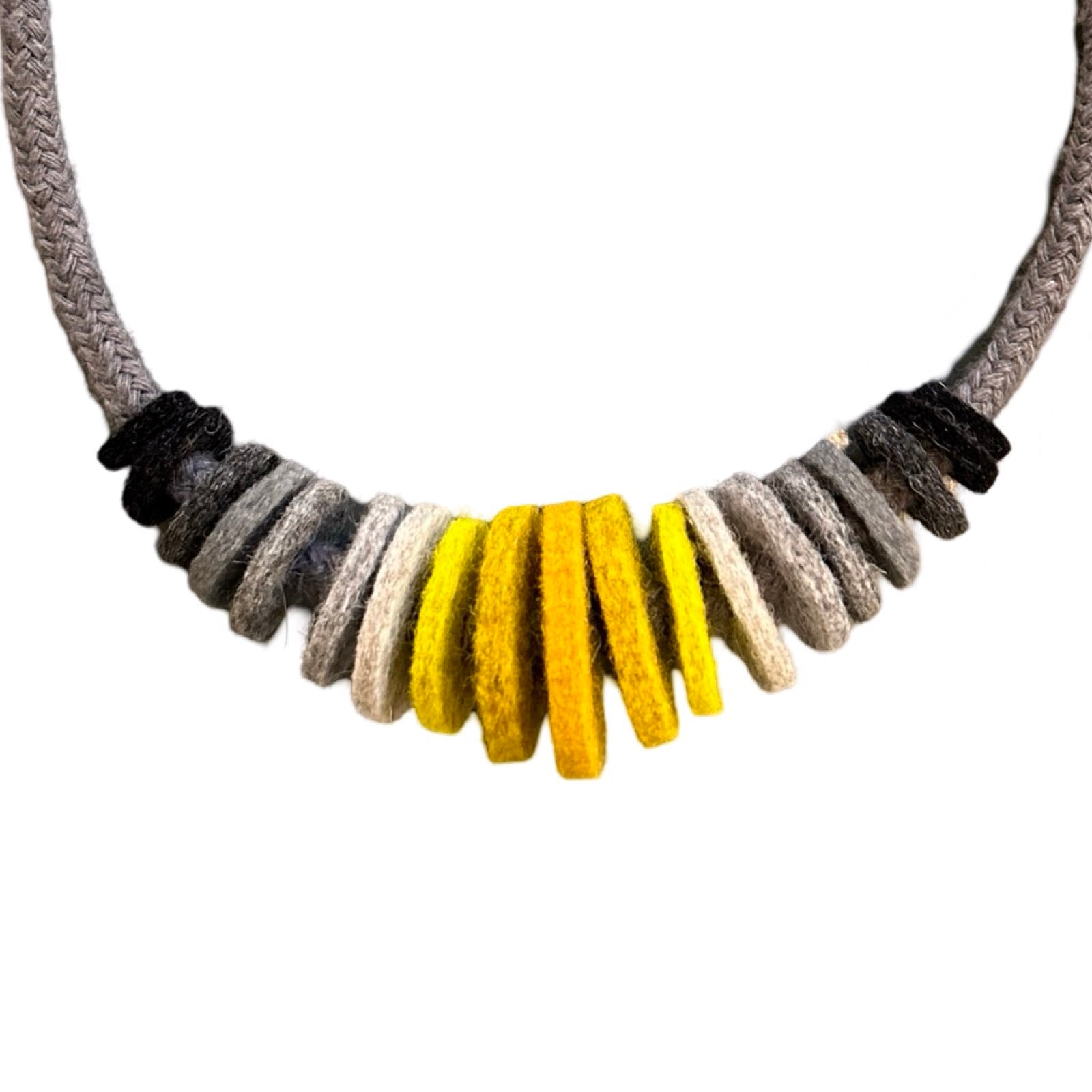 Handmade mustard and grey felt necklace featuring black, dark grey, light grey, yellow and mustard felt circles threaded onto a grey cord, with the largest circles in the centre.