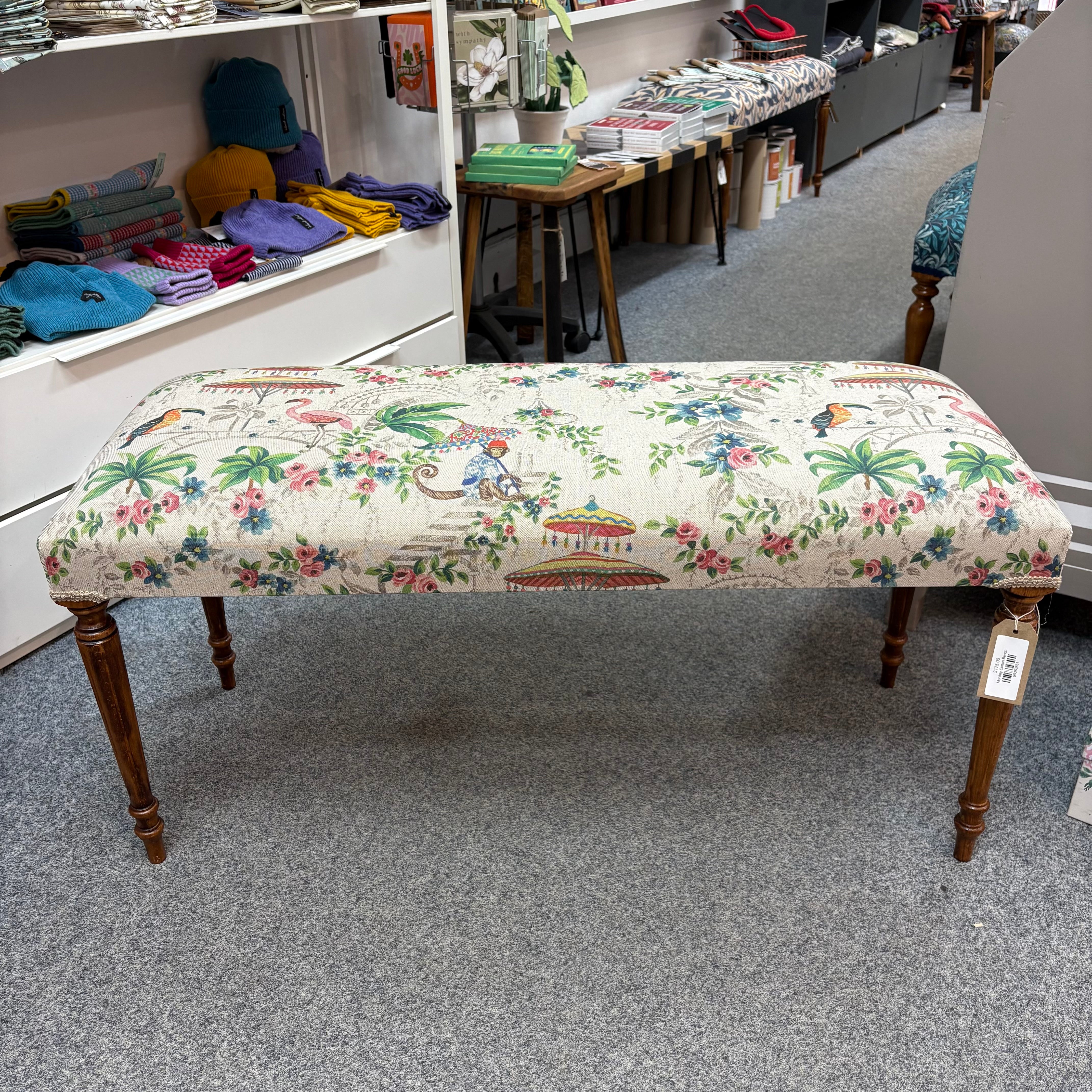 Floral and animal patterned bench in a store setting with shelves and products in the background.
