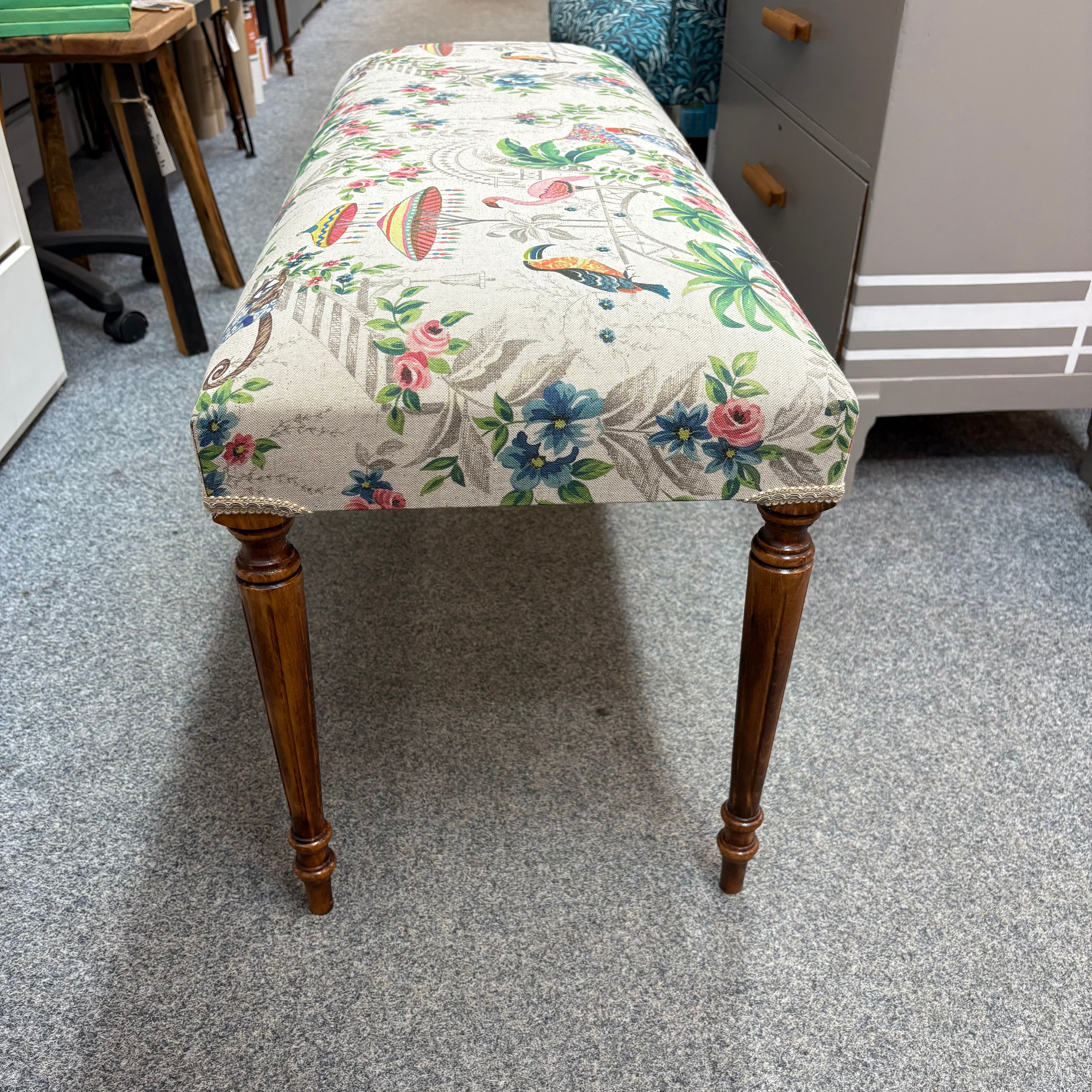 Decorative stool with floral and animal pattern on a grey floor.