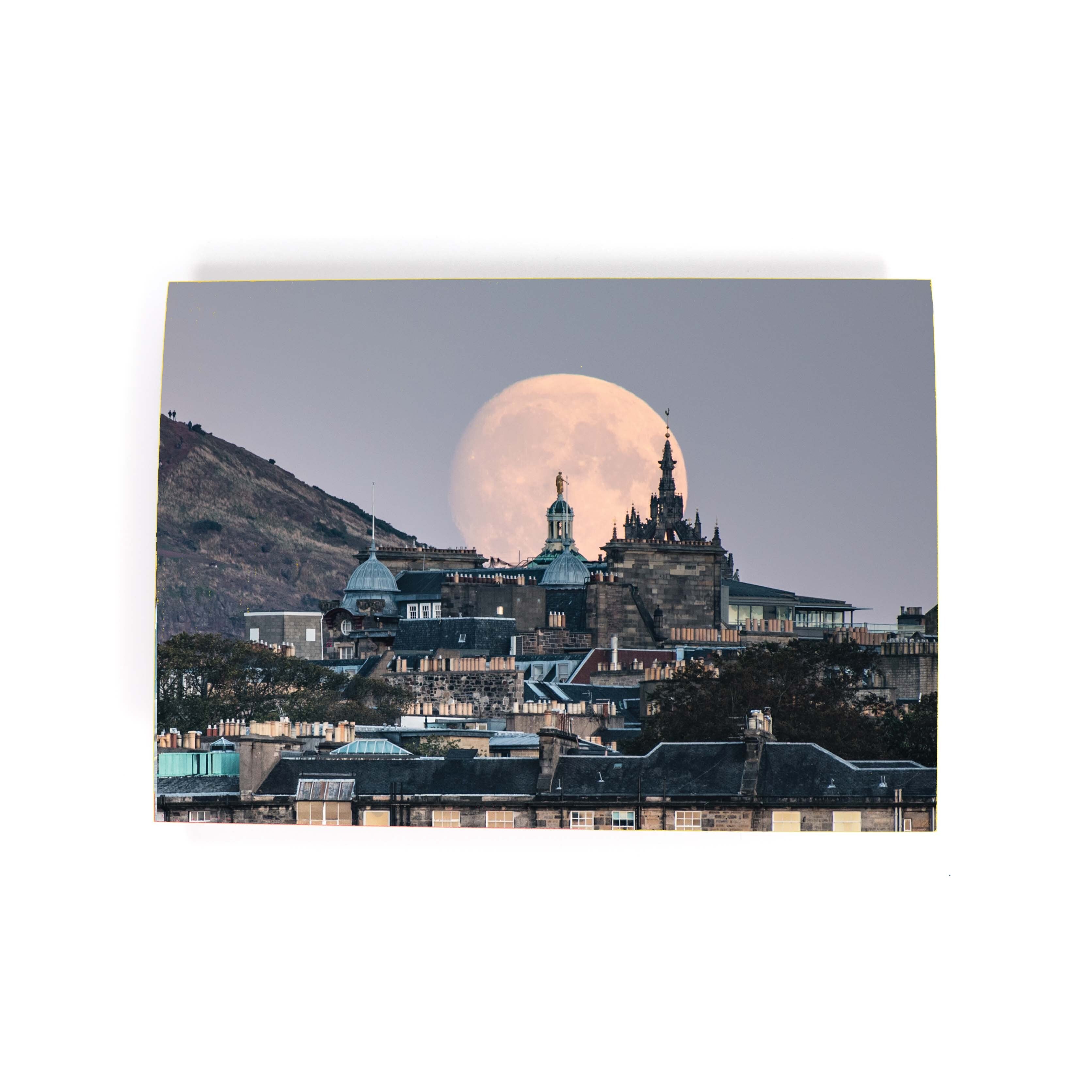 An A6 greeting card of the moon rising, behind the Edinburgh skyline.